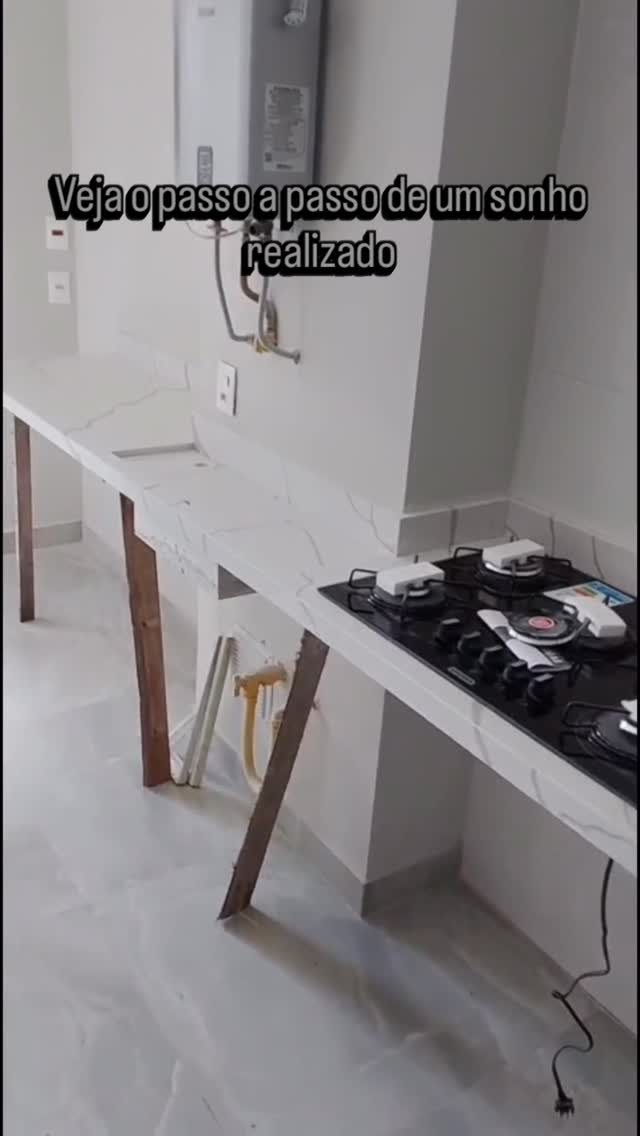 Bancada de cozinha em pedra branca com veios cinza, com recorte para cooktop e cuba