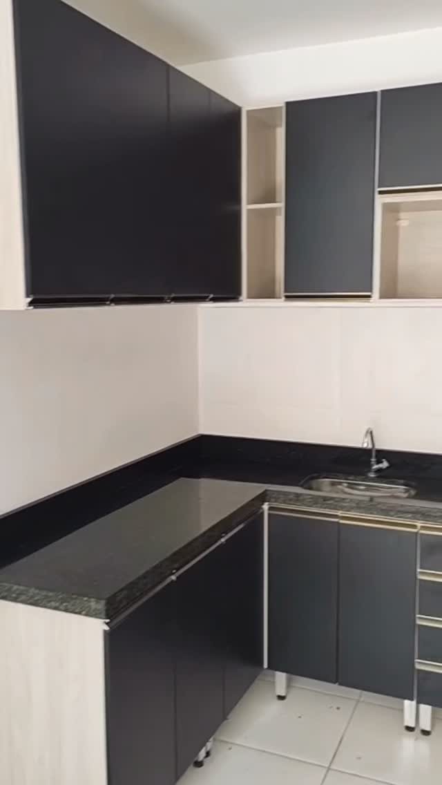 Cozinha em L com bancada de granito escuro, pia de inox e armários